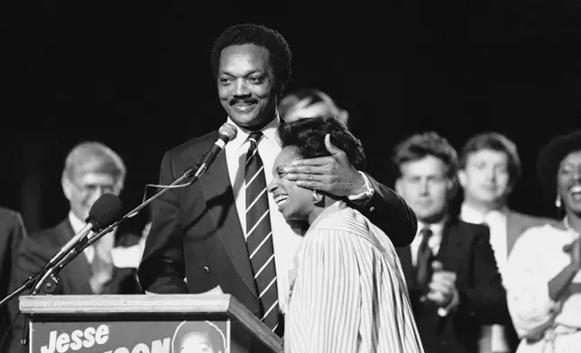 FILE - Democratic presidential candidate Jesse Jackson gives his wife Jacqueline a warm embrace as he takes time out from his political stumping in Los Angeles, May 18, 1984. (AP Photo/Lennox McLendon, File)