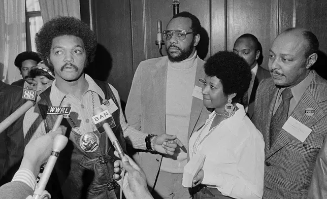 FILE - Rev. Jesse Jackson speaks to reporters at the Operation PUSH Soul Picnic in New York on March 26, 1972. With him are Tom Todd, vice president of PUSH, from second left, Aretha Franklin and Louis Stokes. (AP Photo/Jim Wells, File)