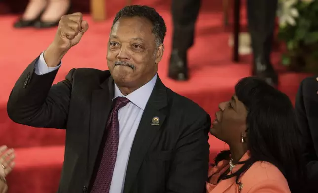 FILE - Rev. Jesse Jackson gestures to a friend in the balcony at the 16th Street Baptist Church in Birmingham, Ala., Sept. 15, 2013. The church held a ceremony honoring the memory of the four young girls who were killed by a bomb placed outside the church 50 years ago by members of the Ku Klux Klan. At right is U.S. Rep. Terri Sewell, D-Ala. (AP Photo/Dave Martin, File)