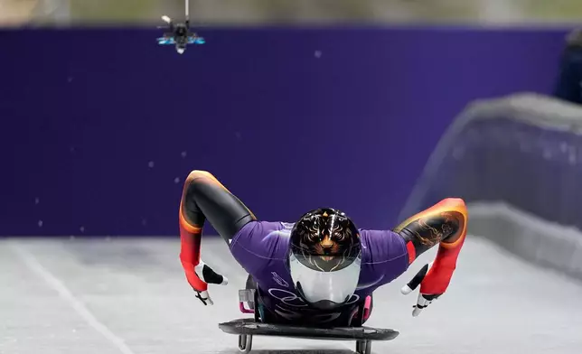 A drone follows China's Lin Qinwei as he starts for a men's skeleton training session at the 2026 Winter Olympics, in Cortina d'Ampezzo, Italy, Tuesday, Feb. 10, 2026. (AP Photo/Aijaz Rahi)