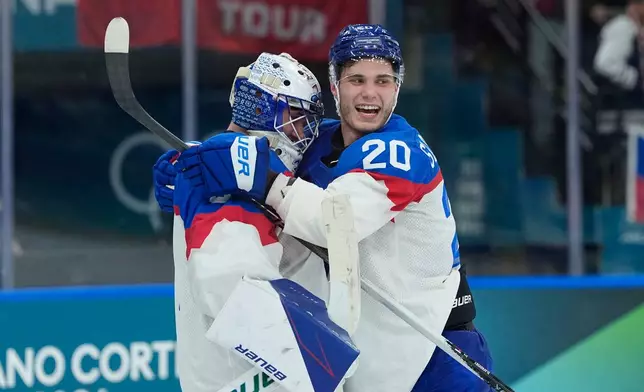 Slovakia's goalkeeper Samuel Hlavaj, left, celebrates with his teammate Slovakia's Juraj Slafkovsky end of a preliminary round match of men's ice hockey between Sweden and Slovakia at the 2026 Winter Olympics, in Milan, Italy, Saturday, Feb. 14, 2026. (AP Photo/Petr David Josek)