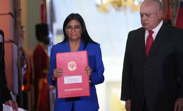 Venezuelan acting President Delcy Rodriguez holds up an amnesty bill approved by the National Assembly alongside Interior Minister Diosdado Cabello at Miraflores Palace in Caracas, Venezuela, Thursday, Feb. 19, 2026. (AP Photo/Ariana Cubillos)