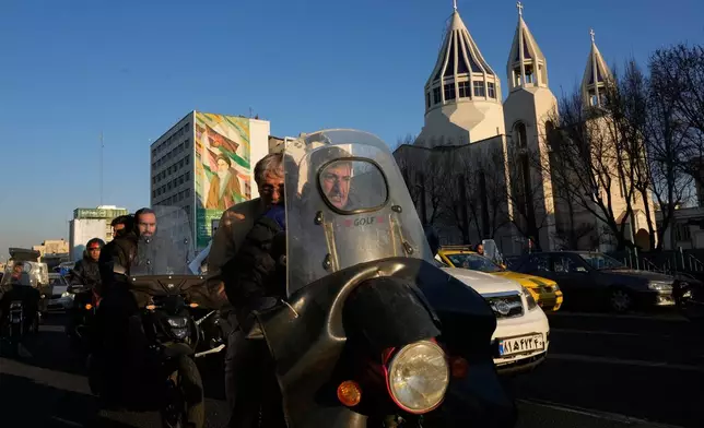 Commuters drive past Saint Sarkis church and a mural of the late Iranian revolutionary founder Ayatollah Khomeini in downtown Tehran, Iran, Wednesday, Feb. 25, 2026. (AP Photo/Vahid Salemi)