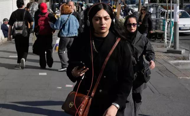 People walk on a sidewalk at Enqelab-e-Eslami, or Islamic Revolution, square in downtown Tehran, Iran, Wednesday, Feb. 25, 2026. (AP Photo/Vahid Salemi)