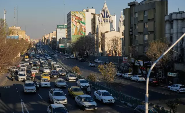Vehicles drive past the Saint Sarkis church and a painting of the late Iranian revolutionary founder Ayatollah Khomeini in downtown Tehran, Iran, Wednesday, Feb. 25, 2026. (AP Photo/Vahid Salemi)