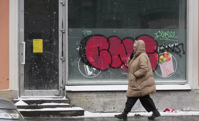 A woman walks past a closed grocery shop in St. Petersburg, Russia, Friday, Feb. 20, 2026. (AP Photo/Dmitri Lovetsky)