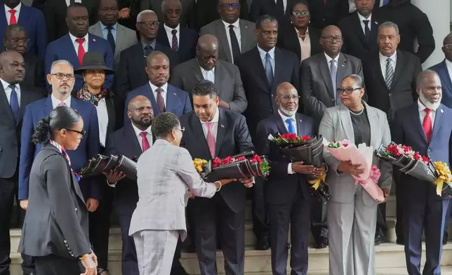 Members of Haiti's presidential council receive bouquets of flowers at a ceremony marking the end of their almost two-year rule, in Port-au-Prince, Saturday, Feb. 7, 2026. (AP Photo/Odelyn Joseph)