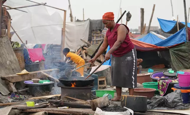 Kpetosi Basra , fried a dough to sell at the ruins of her demolished stills house in Makoko slum in Lagos, Nigeria, Wednesday, Jan. 14, 2026. (AP Photo/Sunday Alamba)