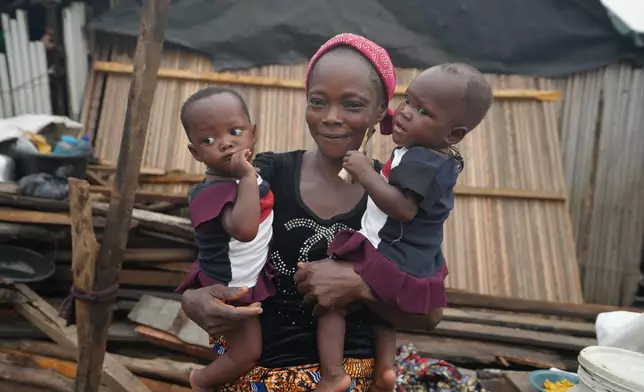 Josianua Agbokpasu poses with her twins at their demolished stilts house in Makoko Lagos, Nigeria, Friday, Jan.30, 2026. (AP Photo/Sunday Alamba)