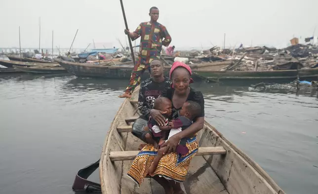 Victor Ahansu, center, and his wife Josianua Agbokpasu, front, ride with their twins inside a canoe in Makoko in Lagos, Nigeria, Friday, Jan.30, 2026. (AP Photo/Sunday Alamba)