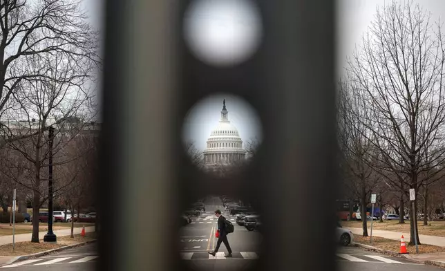A pedestrian walks along Columbus Circle NE near the U.S. Capitol, Thursday, Feb. 26, 2026, in Washington. (AP Photo/Tom Brenner)