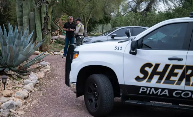 A Pima County Sheriff's deputy talks with a private security guard at Nancy Guthrie's home Thursday, Feb. 5, 2026, in Tucson, Ariz. (AP Photo/Caitlin O'Hara)