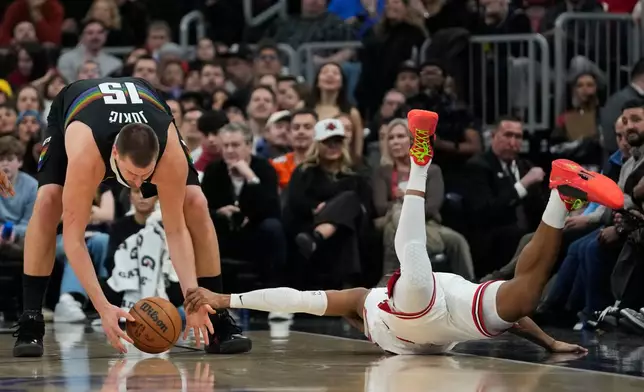 Chicago Bulls forward Isaac Okoro (35), right, slides out of bounds as he fouls Denver Nuggets center Nikola Jokic (15) during the first half of an NBA basketball game Saturday, Feb. 7, 2026, in Chicago. (AP Photo/Erin Hooley)