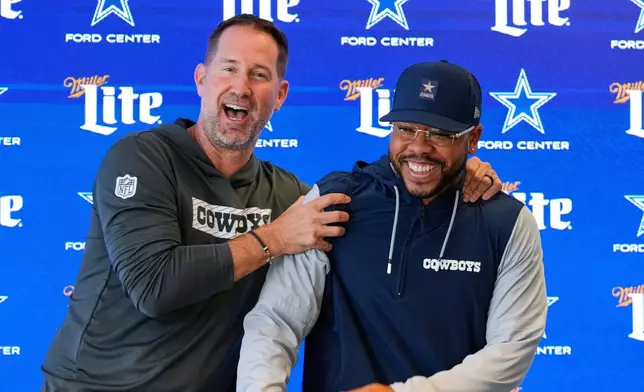 Dallas Cowboys head coach Brian Schottenheimer, left, jokes with Christian Parker at the end of a news conference where Parker was introduced as the new defensive coordinator for the NFL football team, Wednesday, Feb. 18, 2026, in Frisco, Texas. (AP Photo/Tony Gutierrez)