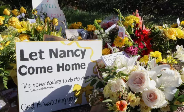 A memorial grows outside the home of Nancy Guthrie, the missing mother of "Today" show host Savannah Guthrie, on Sunday, Feb. 22, 2026, in Tucson, Ariz. (AP Photo/Felicia Fonseca)