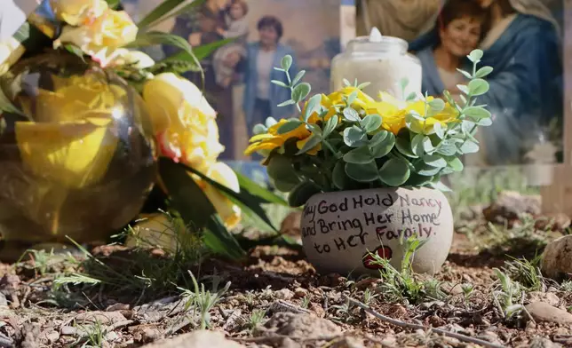 A hand-painted pot is part of a growing memorial outside the home of Nancy Guthrie, the missing mother of "Today" show host Savannah Guthrie, Sunday, Feb. 22, 2026, in Tucson, Ariz. (AP Photo/Felicia Fonseca)