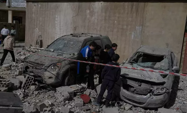 People inspect damaged cars near a building destroyed in an Israeli strike in the village of Temnine in eastern Lebanon, Saturday, Feb. 21, 2026. (AP Photo/Bilal Hussein)