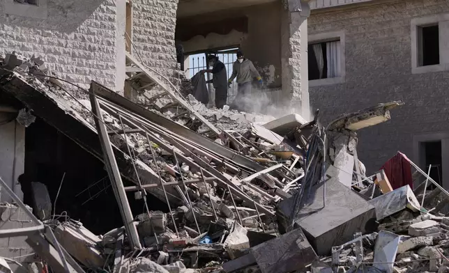 People collect the remains of their belongings from a building destroyed in an Israeli strike in the village of Bednayel in eastern Lebanon, Saturday, Feb. 21, 2026. (AP Photo/Bilal Hussein)