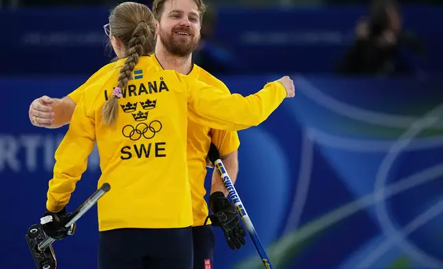 Sweden's Rasmus Wranaa hugs Isabella Wranaa during the semi-finals round of the mixed doubles curling match against Britain, at the 2026 Winter Olympics, in Cortina d'Ampezzo, Italy, Monday, Feb. 9, 2026. (AP Photo/Fatima Shbair)