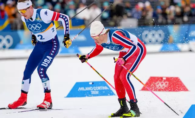 Ben Ogden, of the United States, left, and Johannes Hoesflot Klaebo, right, compete in the cross-country skiing men's sprint classic at the 2026 Winter Olympics, in Tesero, Italy, Tuesday, Feb. 10, 2026. (AP Photo/Kirsty Wigglesworth)