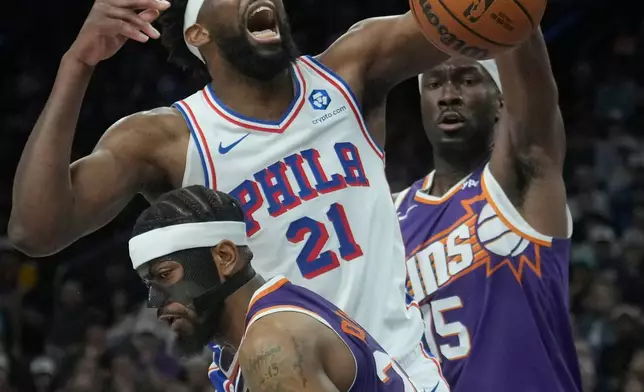 Philadelphia 76ers center Joel Embiid (21) is fouled by Phoenix Suns guard Jordan Goodwin, front, as Suns center Mark Williams (15) defends during the first half of an NBA basketball game Saturday, Feb. 7, 2026, in Phoenix. (AP Photo/Ross D. Franklin)
