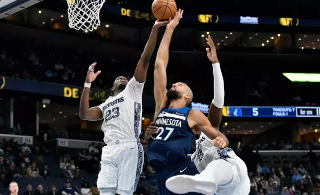 Memphis Grizzlies forward Cedric Coward (23), Minnesota Timberwolves center Rudy Gobert (27) and forward Jaren Jackson Jr. (8) reach for the ball in the first half of an NBA basketball game Monday, Feb. 2, 2026, in Memphis, Tenn. (AP Photo/Brandon Dill)