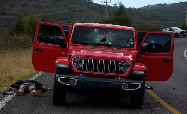 A body lies beside a bullet-riddled vehicle in Tapalpa, Mexico, Monday, Feb. 23, 2026, a day after the Mexican army killed Jalisco New Generation Cartel leader Nemesio Oseguera Cervantes, known as "El Mencho." (AP Photo/Marco Ugarte)