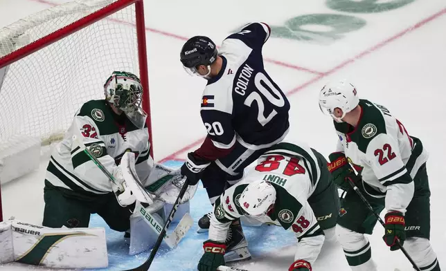 Colorado Avalanche center Ross Colton, second from left, puts a shot on Minnesota Wild goaltender Filip Gustavsson, left, after driving past defenseman Daemon Hunt, third form left, and right wing Danila Yurov in the third period of an NHL hockey game Thursday, Feb. 26, 2026, in Denver. (AP Photo/David Zalubowski)