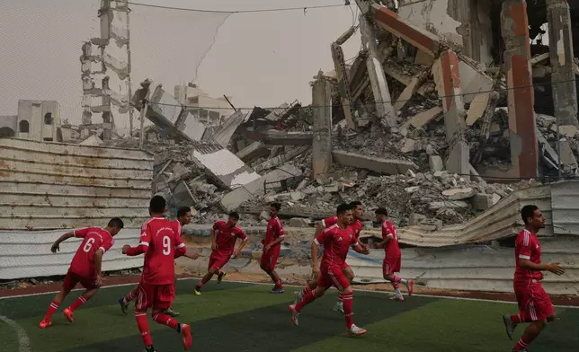 Palestinian players of Al-Ahly Club warm up before a soccer match with Gaza Sports Club at a newly constructed field surrounded by buildings destroyed in Israeli ground and air operations, in Gaza City, Saturday, Feb. 14, 2026. (AP Photo/Jehad Alshrafi)