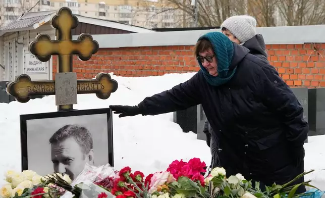 Late Russian opposition leader Alexei Navalny's mother Lyudmila Navalnaya touches his portrait at his grave, two years after his death, at the Borisovskoye Cemetery in Moscow, on Monday, Feb. 16, 2026. (AP Photo/Alexander Zemlianichenko)