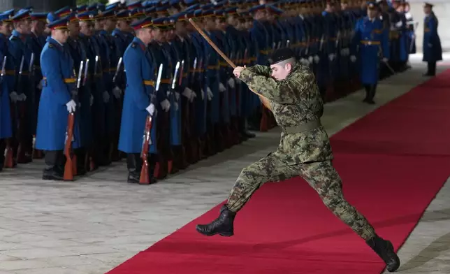 A member of the Serbian honor guard jumps over the red carpet holding a broom before a welcoming ceremony for visiting Azerbaijan President Ilham Aliyev in Belgrade, Serbia, Sunday, Feb. 15, 2026. (AP Photo/Darko Vojinovic)