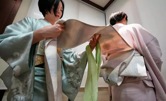 Nao Shimizu, Representative Director of Kimono Sunao Co., Ltd., left, demonstrates various ways of tying an obi on Emiko Terai during a kimono presentation in Tokyo on Tuesday, Nov. 11, 2025. (AP Photo/Eugene Hoshiko)