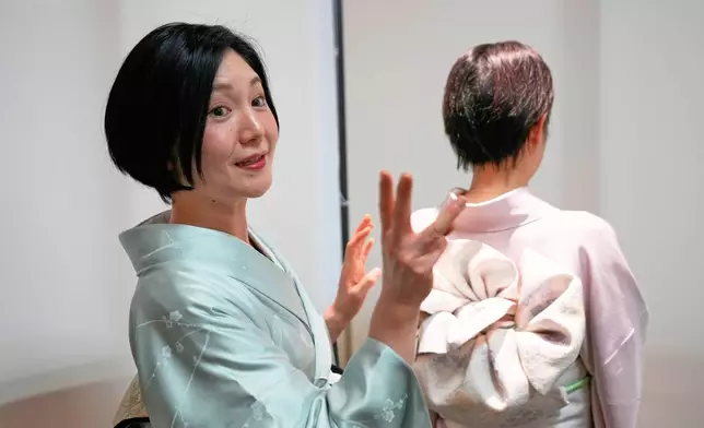 Nao Shimizu, Representative Director of Kimono Sunao Co., Ltd., left, demonstrates various ways of tying an obi on dressing assistant Emiko Terai during a kimono presentation in Tokyo on Tuesday, Nov. 11, 2025. (AP Photo/Eugene Hoshiko)
