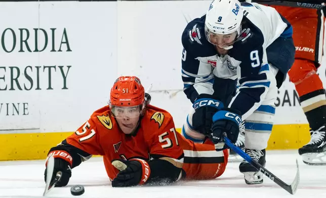 Anaheim Ducks defenseman Olen Zellweger, left, and Winnipeg Jets left wing Alex Iafallo (9) vie for the puck during the second period of an NHL hockey game, Friday, Feb. 27, 2026, in Anaheim, Calif. (AP Photo/Kyusung Gong)