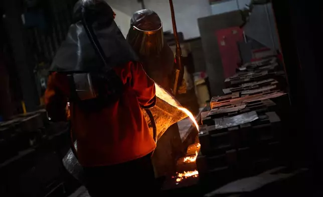 Furnace workers pour molten metal as part of the process to create BAFTA masks at FSE Foundry in Braintree, England on Tuesday, Feb. 10, 2026. (Scott A Garfitt/Invision/AP)