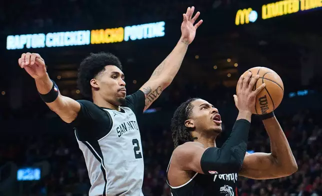 Toronto Raptors' Collin Murray-Boyles (12) drives to the net past San Antonio Spurs' Dylan Harper (2) during the first half of an NBA basketball game, in Toronto, Wednesday, Feb. 25, 2026. (Sammy Kogan/The Canadian Press via AP)