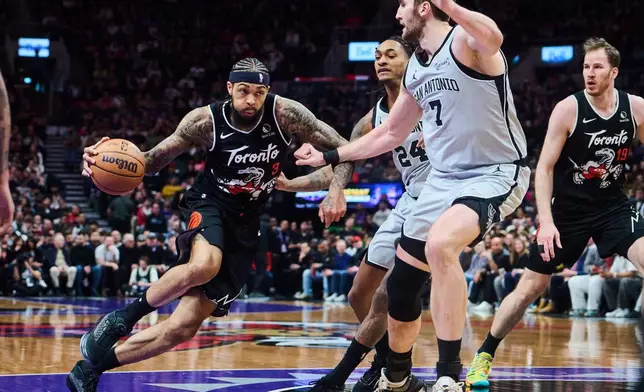 Toronto Raptors' Brandon Ingram (3) drives through San Antonio Spurs' Devin Vassell (24), centre, and Luke Kornet (7) during the first half of an NBA basketball game in Toronto, Wednesday, Feb. 25, 2026. (Sammy Kogan/The Canadian Press via AP)