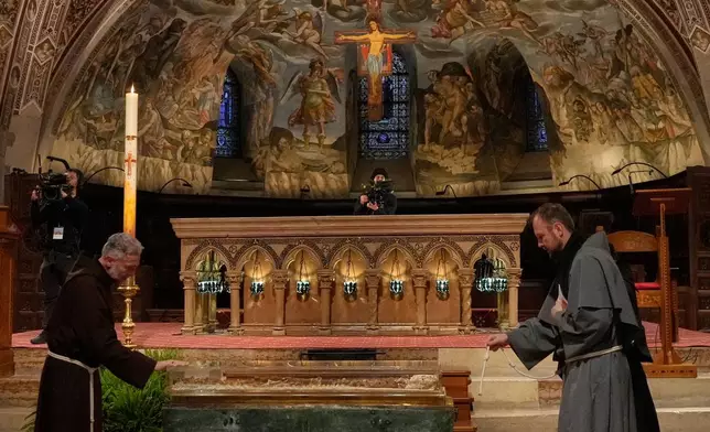 Friars pray before the remains of Francis of Assisi inside the Basilica of St. Francis of Assisi in Assisi, Italy, Saturday, Feb. 21, 2026, on the eve of a public exposition beginning Feb. 22 to mark the 800th anniversary of his death in 1226. (AP Photo/Gregorio Borgia)