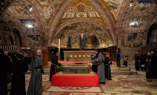 Friars pray before the remains of Francis of Assisi inside the Basilica of St. Francis of Assisi in Assisi, Italy, Saturday, Feb. 21, 2026, on the eve of a public exposition beginning Feb. 22 to mark the 800th anniversary of his death in 1226. (AP Photo/Gregorio Borgia)