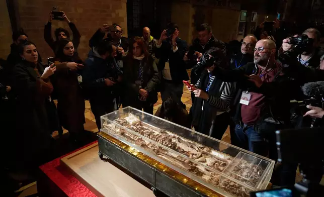Journalists record the remains of Francis of Assisi inside the Basilica of St. Francis of Assisi in Assisi, Italy, Saturday, Feb. 21, 2026, on the eve of a public exposition beginning Feb. 22 to mark the 800th anniversary of his death in 1226. (AP Photo/Gregorio Borgia)