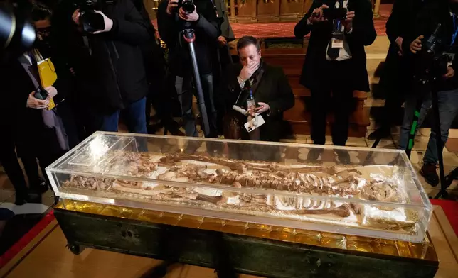 Journalists record the remains of Francis of Assisi inside the Basilica of St. Francis of Assisi in Assisi, Italy, Saturday, Feb. 21, 2026, on the eve of a public exposition beginning Feb. 22 to mark the 800th anniversary of his death in 1226. (AP Photo/Gregorio Borgia)
