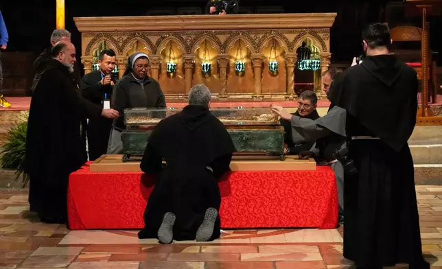 Friars and a nun pray before the remains of Francis of Assisi inside the Basilica of St. Francis of Assisi in Assisi, Italy, Saturday, Feb. 21, 2026, on the eve of a public exposition beginning Feb. 22 to mark the 800th anniversary of his death in 1226. (AP Photo/Gregorio Borgia)