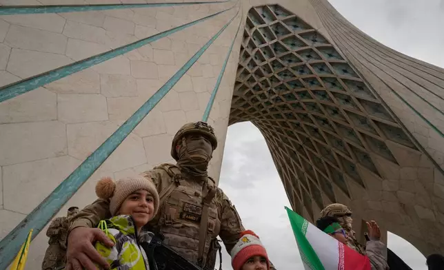 Members of Iran's Revolutionary Guard poses for pictures with children as they stand guard near the Azadi ( Freedom ) monument during the annual rally commemorating the 1979 Islamic Revolution at Azadi Square in Tehran, Iran, Wednesday, Feb. 11, 2026. (AP Photo/Vahid Salemi)