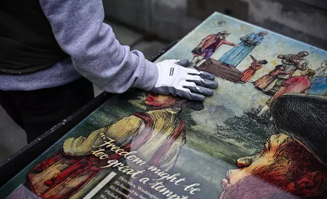 A National Parks Service worker puts his hand on a panel that was part of an exhibit on slavery at the President's House Site in Philadelphia to be put back Thursday, Feb. 19, 2026. (AP Photo/Joe Lamberti)