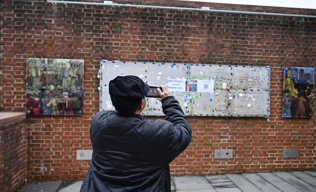 A person takes a photo as panels that were part of an exhibit on slavery at the President's House Site in Philadelphia are put back Thursday, Feb. 19, 2026. (AP Photo/Joe Lamberti)