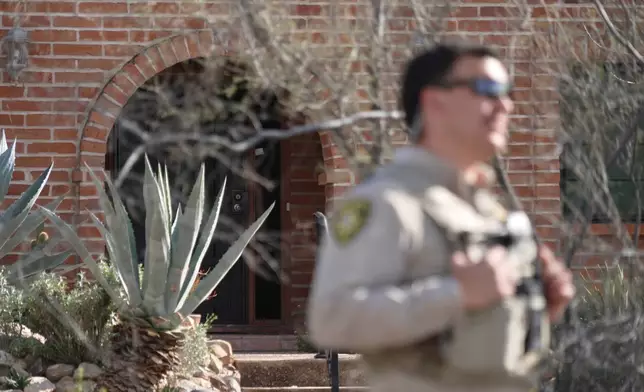 A member of the Pima County Sheriff's Department stands in front of the front door of the house of Nancy Guthrie, the missing mother of “Today” show host Savannah Guthrie, Tuesday, Feb. 10, 2026, in Tucson, Ariz. (AP Photo/Ty ONeil)