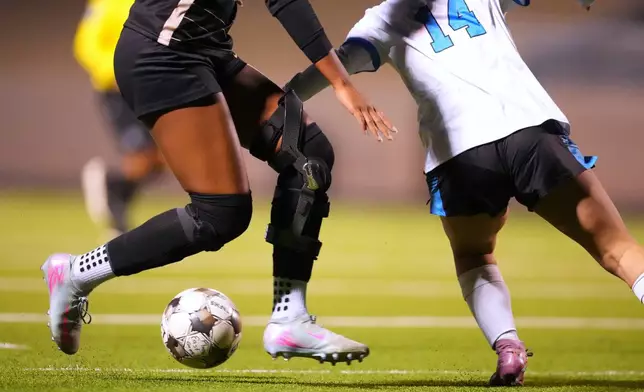 Plano East varsity soccer player Aliya Jacob's knee brace, left, is visible as she attacks Rock Hill's Adalina Flores during a soccer game, Jan. 30, 2026, in Murphy, Texas. (AP Photo/Julio Cortez)