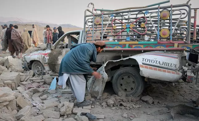 A man inspects a damaged car at the site of a cross-border Pakistani army strike in the Behsud district of Nangarhar province, Afghanistan, Sunday, Feb. 22, 2026. (AP Photo/Hedayat Shah)