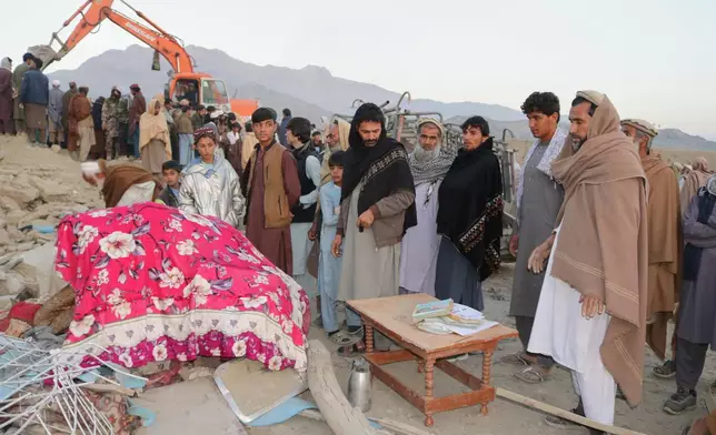 Local residents gather as bulldozer clears the rubble of a house hit by a cross-border Pakistani army strike in the Behsud district of Nangarhar province, Afghanistan, Sunday, Feb. 22, 2026. (AP Photo/Hedayat Shah)