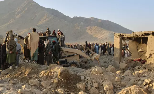 Local residents and civil defense workers look on as a bulldozer clears the rubble of a house hit by a cross-border Pakistani army strike in the Behsud district of Nangarhar province, Afghanistan, Sunday, Feb. 22, 2026. (AP Photo/Hedayat Shah)